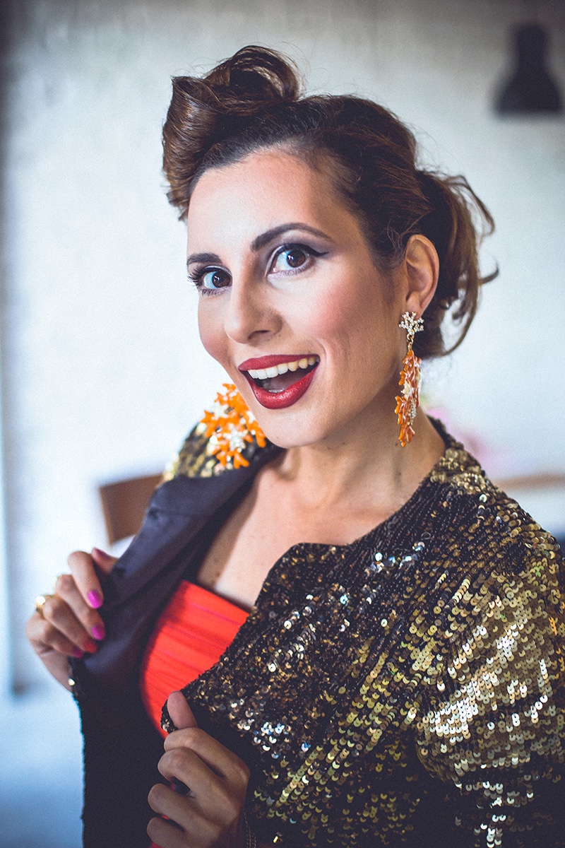 Portret sa osmehom — zlatna šljokičasta jakna i koralne minđuše