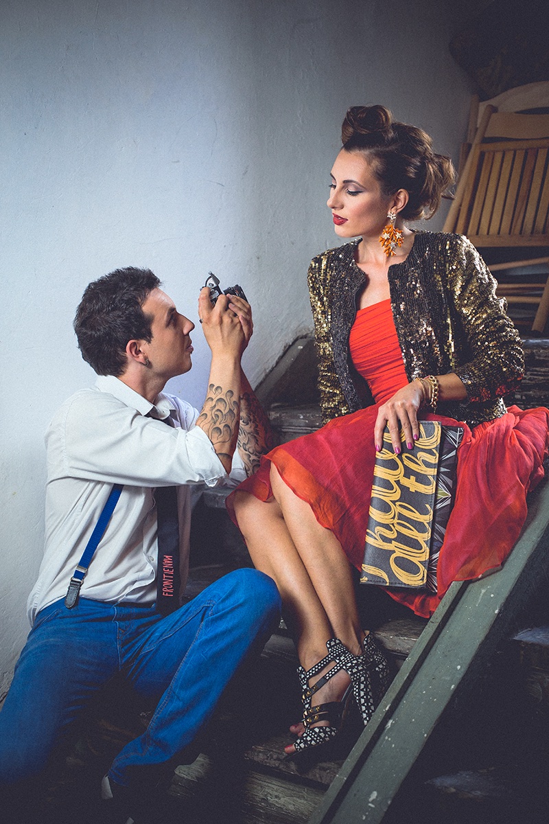 On fotografiše nju na stepenicama — zlatna jakna i crvena suknja, drugi ugao