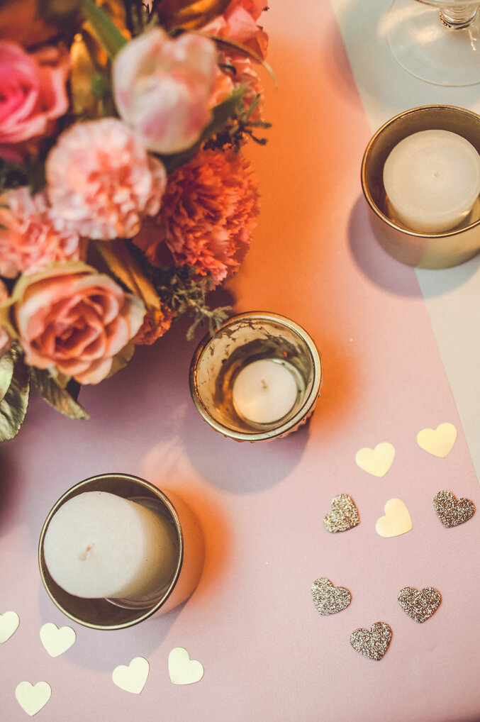 Sveće u zlatnim držačima sa zlatnim glitter srcima na roze stolnjaku i buket roze ruža