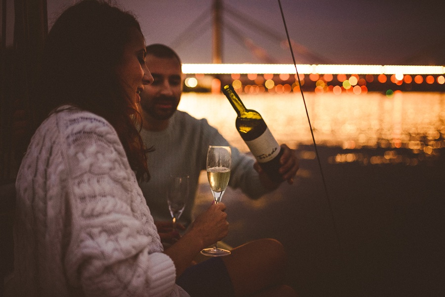 Noć na jedrilici — svetla se ogledaju u reci