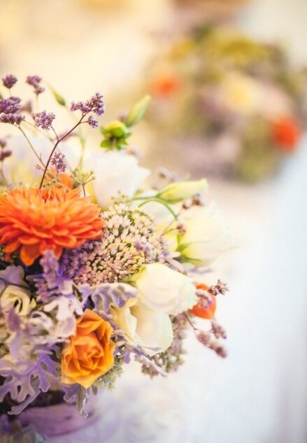 Cvetni aranžman krupni plan — narandžaste i lila nijanse