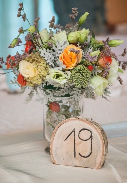 Stolovi za goste — cvetna dekoracija sa drvenim brojevima
