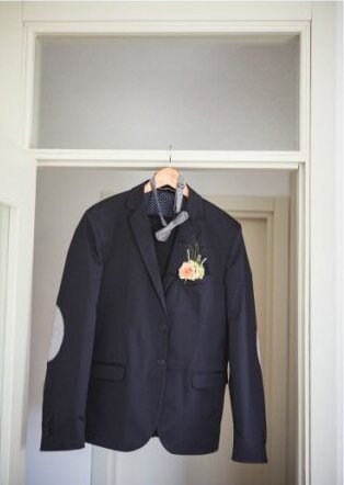 Mladoženjino odelo na vešalici sa leptirkom i butonijerkom