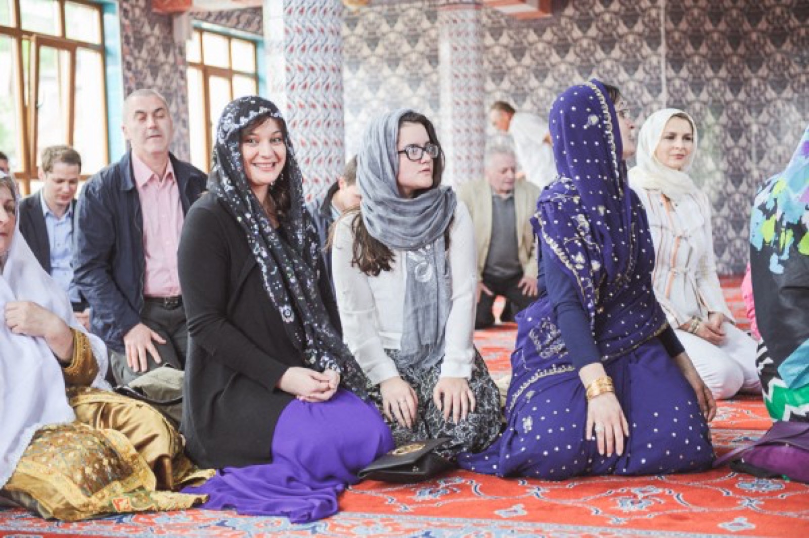 Gosti u tradicionalnim nošnjama unutar džamije — žarke boje na orijentalnom tepihu