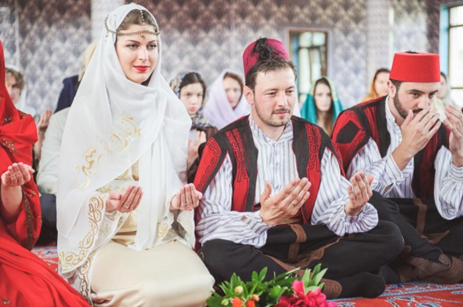 Ceremonija u džamiji — gosti u nošnjama, cveće na orijentalnom tepihu