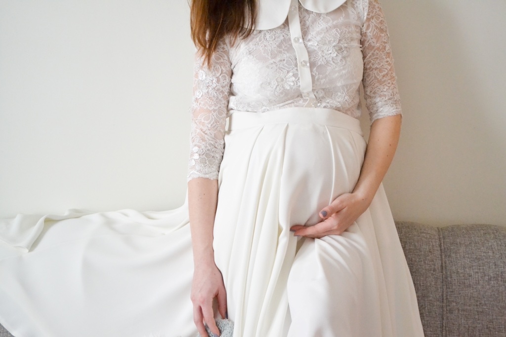 Bela haljina sa čipkom na sofi — detalj materijala i kroja