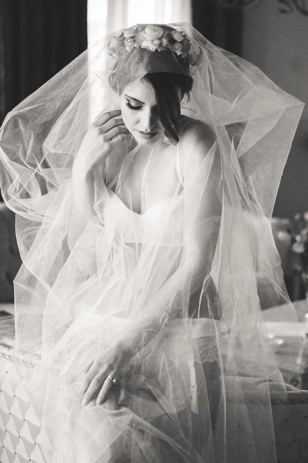 Model u belom velu kraj prozora — meka svetlost, intimna atmosfera
