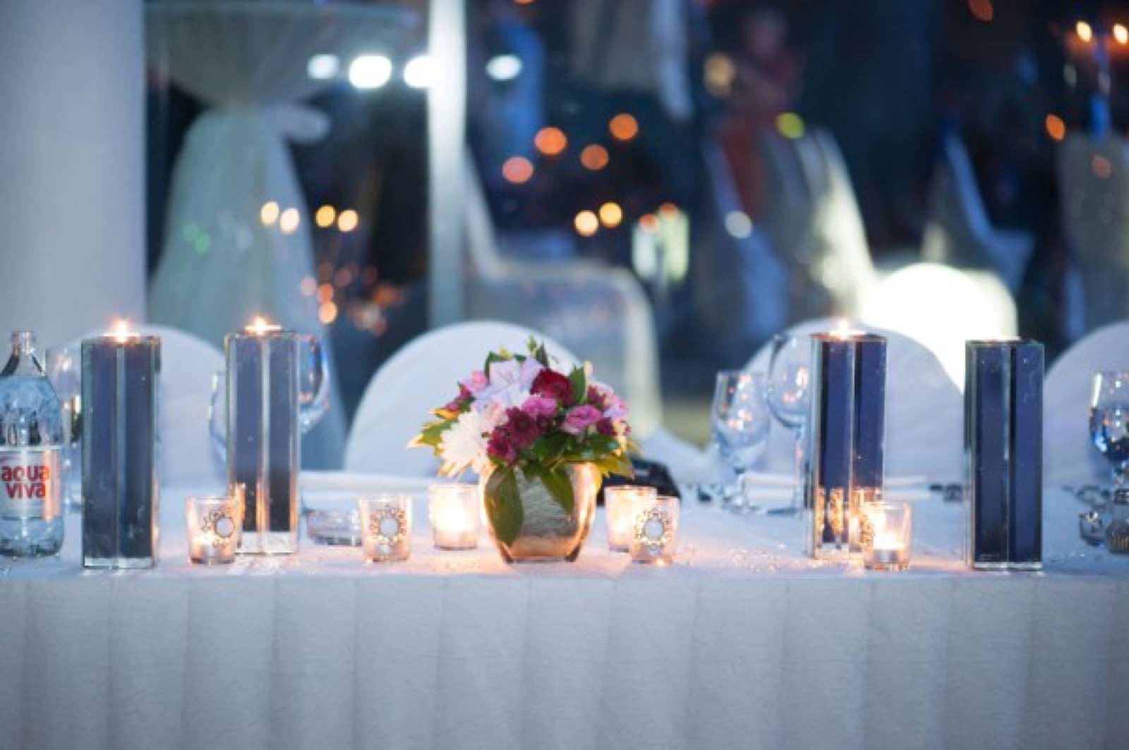 Dekoracija — sveće i bele cvetne aranžmane, ljubičasto svetlo